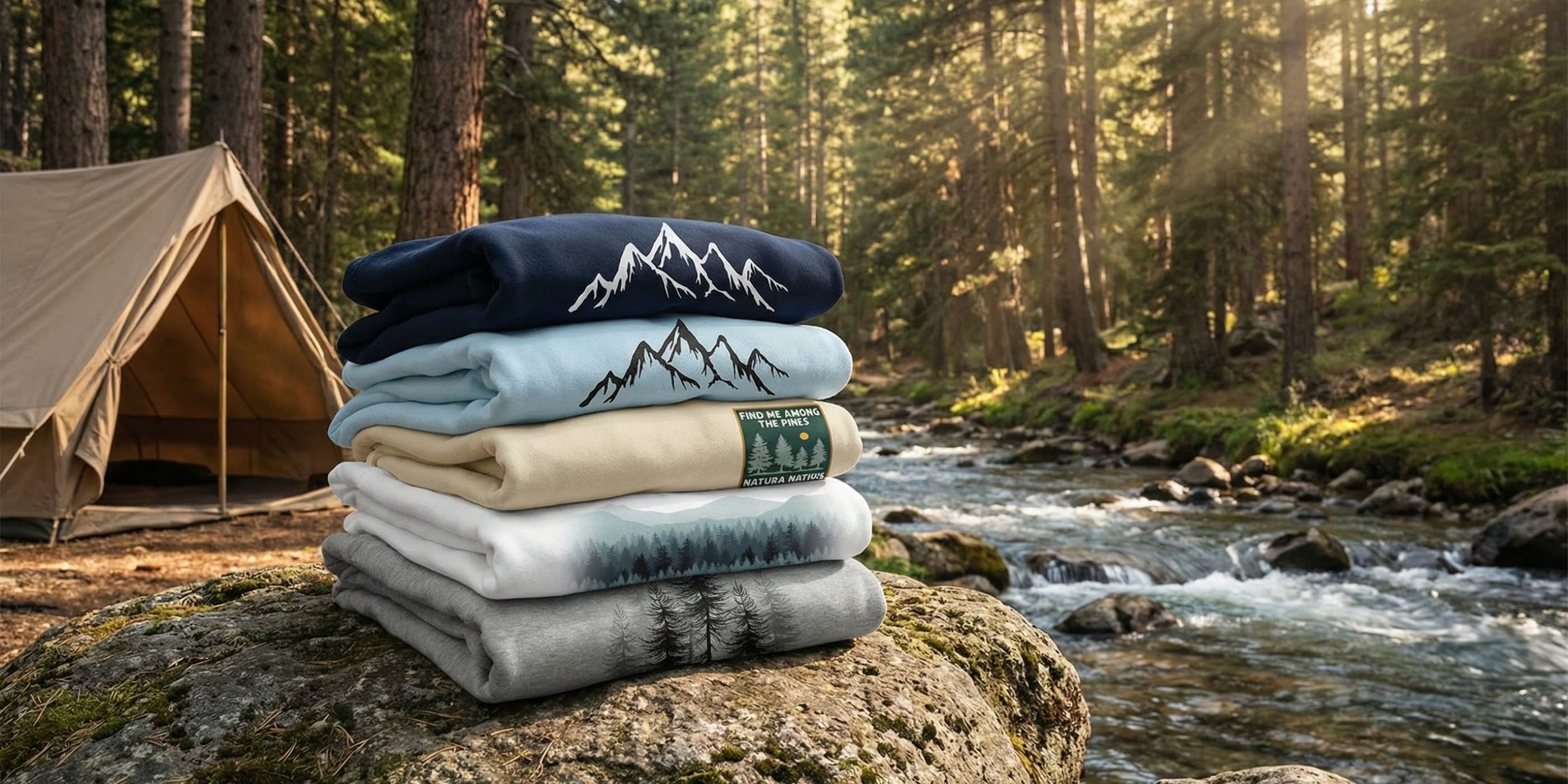 A stack of Nature Sweatshirts on a rock in the forest next to a flowing river  – Part of the Natura Nation Nature Sweatshirts collection.