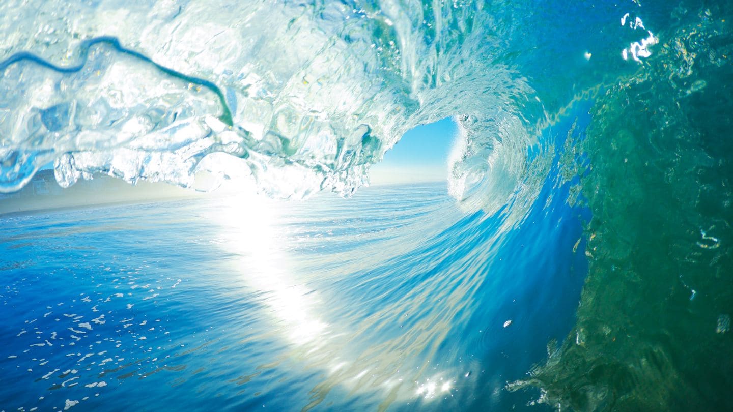 Powerful tunnel wave over the sea representing Natura Nation’s Ocean Clothing Collection