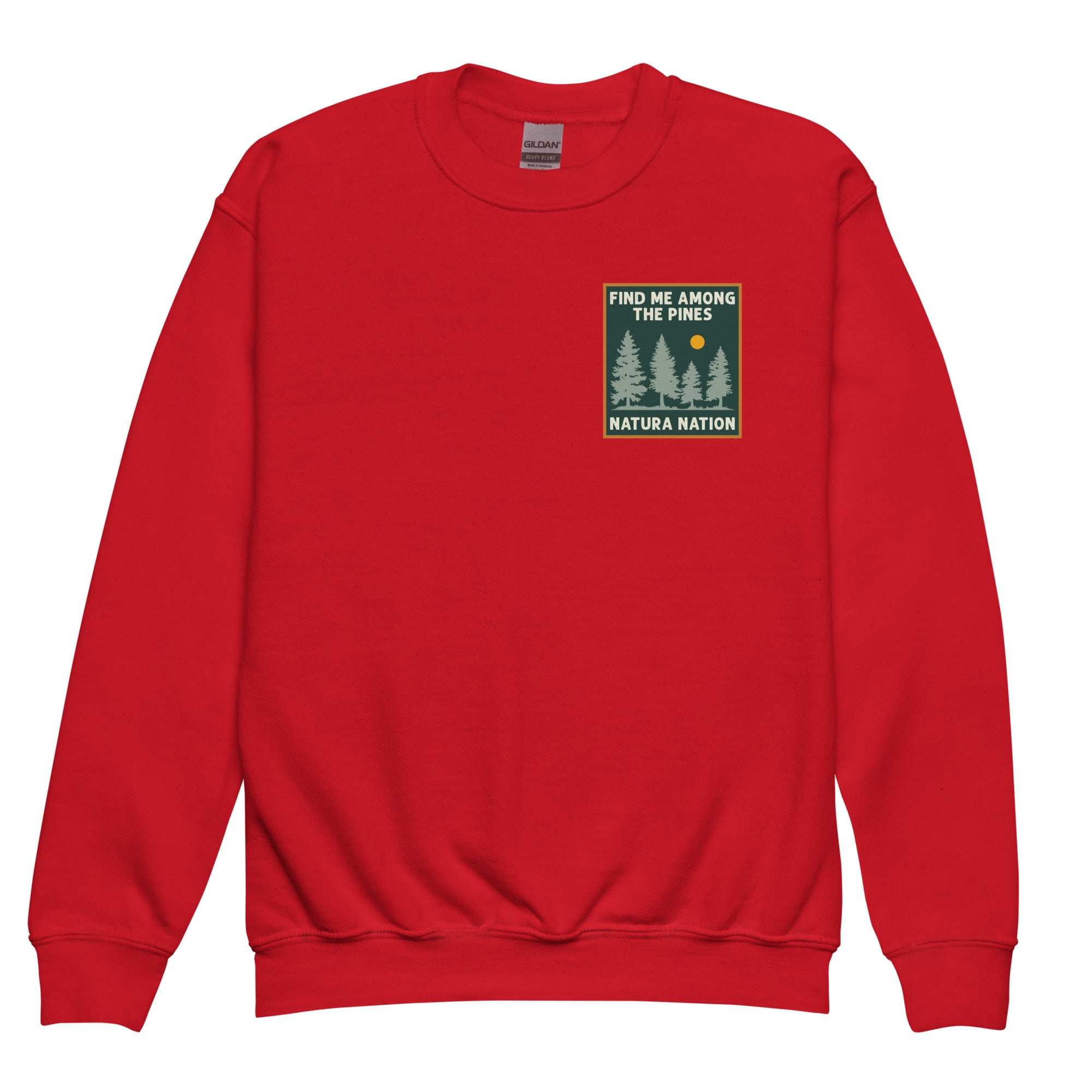 A red crewneck sweatshirt with a small square chest graphic on the left side. The graphic features a dark green background with the text 'FIND ME AMONG THE PINES' at the top and 'NATURA NATION' at the bottom, with three pine trees and a small yellow sun in the center. Kids nature crewneck sweatshirt featuring pine trees for teens and youth.