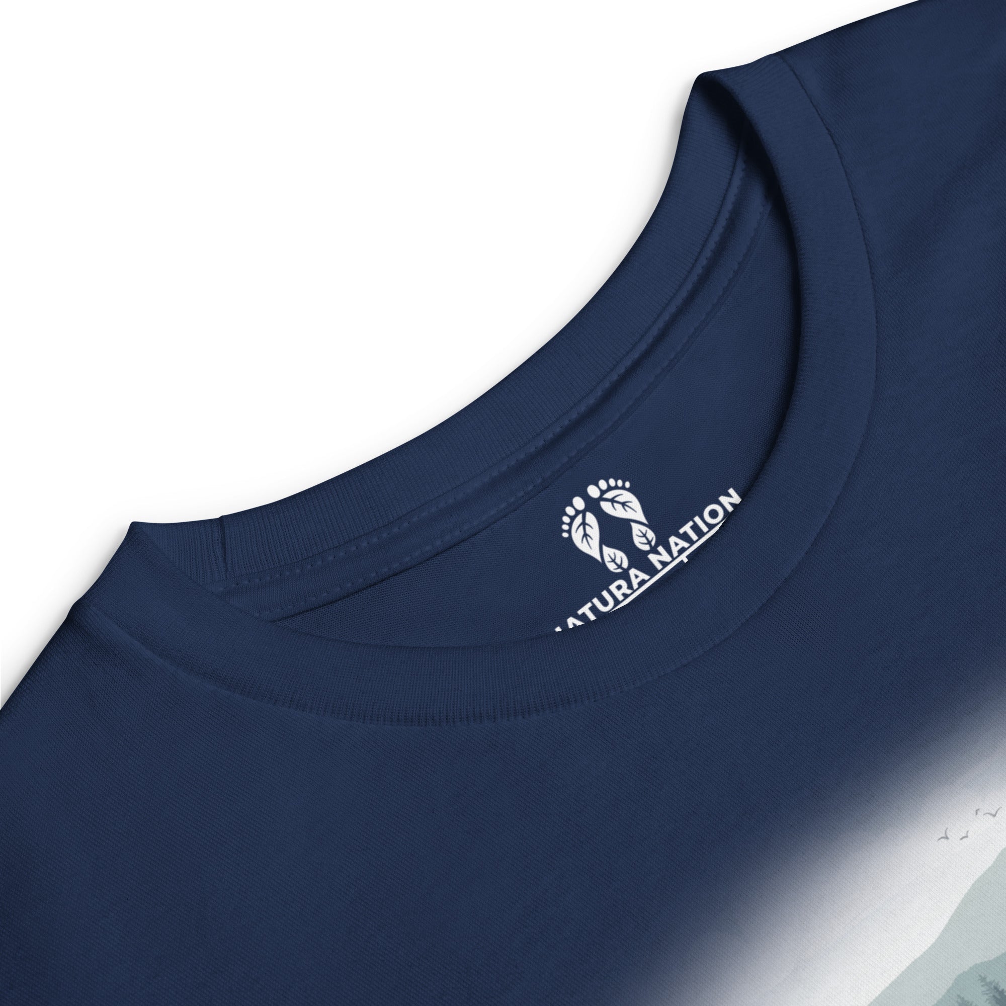 Close-up of a navy blue long-sleeve t-shirt showing the inner neck label with a white 'NATURA NATION' logo and footprint graphic. Long-sleeve nature tee for teens with trees and mountains.