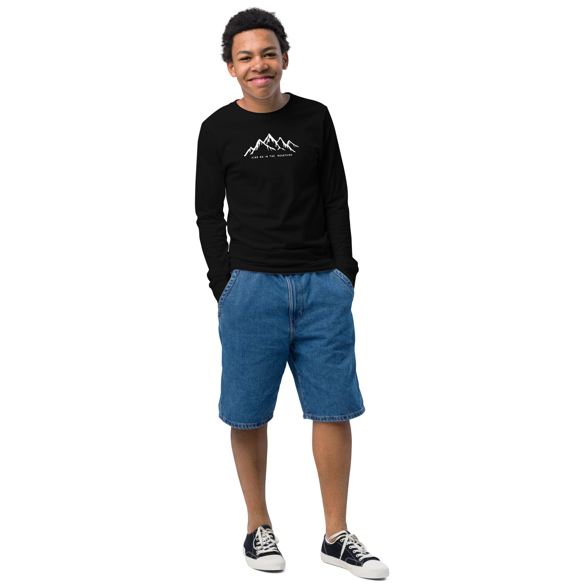 A teen wearing a black long-sleeve tee with a white graphic FIND ME IN THE MOUNTAINS made by Natura Nation.